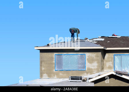 Konzept des Bauprozesses. Qualifizierte Bauarbeiter, Asphalt Dachschindeln, der auf dem Dach eines neuen Hauses. Stockfoto