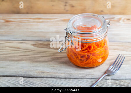 Koreanische Karotten in Gläsern auf einem Holztisch Stockfoto