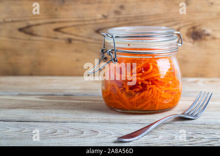 Koreanische Karotten in Gläsern auf einem Holztisch Stockfoto