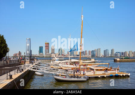 New York, USA - 8. Juli 2018: Boote bei North Cove Yacht Hafen mit Jersey City Skyline im Abstand vertäut. Stockfoto