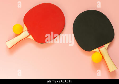 Schwarz und Rot Tennis ping pong Schläger und orange Kugeln auf einem rosa Hintergrund isoliert, Sport Ausrüstung für Tischtennis Stockfoto