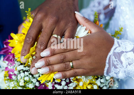 Weiße und schwarze Hand United - Pflegt die Hände über Trauringe beigetreten - Goldene Hochzeit Ringe Stockfoto