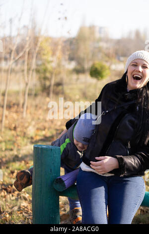 Mutter - ein im mittleren Alter Junge brünette Frau spielt mit ihrem dreijährigen Sohn an einem sonnigen Herbsttag. Fröhliche Stimmung, lächeln Stockfoto