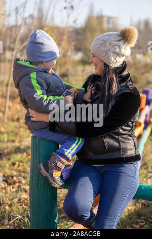 Mutter - ein im mittleren Alter Junge brünette Frau spielt mit ihrem dreijährigen Sohn an einem sonnigen Herbsttag. Fröhliche Stimmung, lächeln Stockfoto