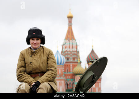 Frau Soldat in Uniform der Sowjetischen Armee sitzen auf russischen Tank während einer historischen Parade auf dem Roten Platz auf St. Basils Kathedrale im Hintergrund. 23. Februar Stockfoto