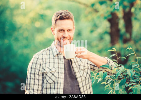Grüner Tee Plantage. Vollständige blatt Tee. Hervorragender Geschmack. Genießen Sie heiße Getränke. Natürliche trinken. Gesunde Lebensweise. Ich bevorzuge grünen Tee. Erfrischendes Getränk. Man bärtige Kaffee Bauer halten Becher Natur Hintergrund. Stockfoto
