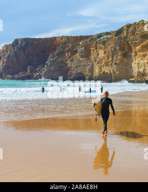 SAGRES, PORTUGAL - Oktober 30, 2018: Junger Mann zu Fuß vom Sandstrand mit Surfbrett. Die ALgarve ist eine berühmte Surfen in Portugal Stockfoto