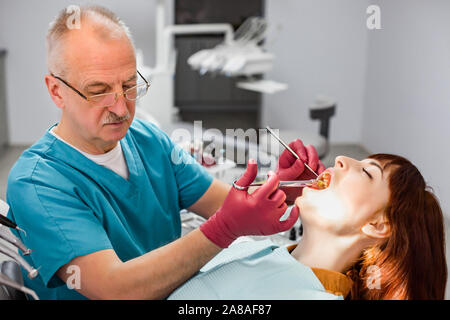 Junge schöne Frau, zahnärztliche Anästhesie, closeup erschossen. Älterer männlicher Arzt Vorbereitung der Patienten auf die Behandlung. Stockfoto