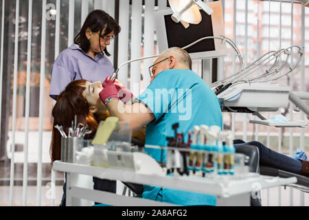 Team professioneller Zahnärzte, Mann und Frau, die Behandlung für die junge Frau, die Patienten in ihrer Chirurgie Zahnklinik. Stockfoto