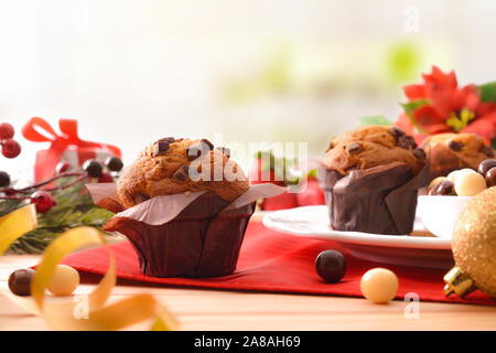 Muffins mit Schokoladenstückchen auf Holztisch mit Weihnachten Objekte eingerichtet. Horizontale Komposition. Vorderansicht. Stockfoto