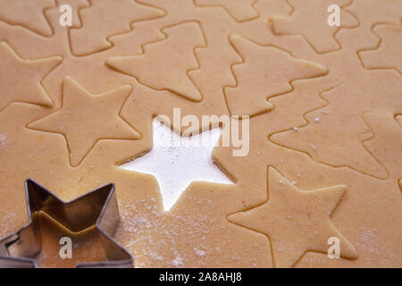 Nahaufnahme von Ausschneiden Weihnachten Kekse in Form von Sternen und Bäume aus dem ausgerollten Teig Stockfoto