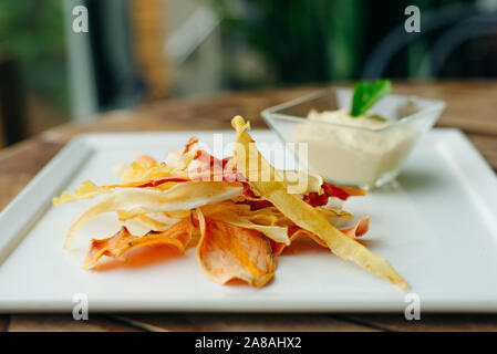 Hummus mit Wurzelgemüse Farbe Chips im Restaurant Stockfoto