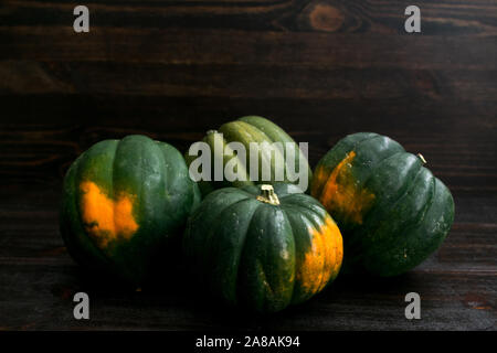 Rustikale Gruppierung von Acorn Squash auf einem dunklen Hintergrund Stockfoto