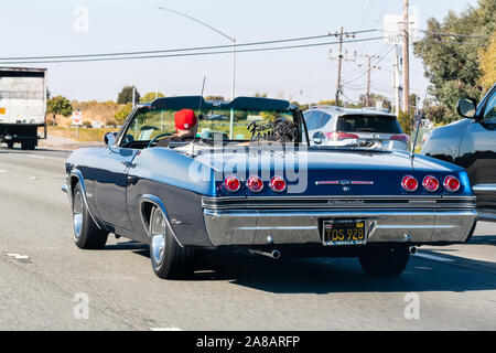 Okt 26, 2019 San Francisco/CA/USA - 1965 Chevrolet Impala SS Fahren auf der Autobahn; die Frisco beste Auto Club Logo auf dem Auto angezeigt. Stockfoto