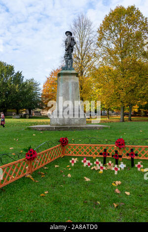 Roter Mohn am Kreuze für Tag der Erinnerung mit einer Statue eines Soldaten im Hintergrund Stockfoto