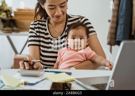 Frau mit Baby, Arbeit von zu Hause aus Ihren Online Shop Stockfoto