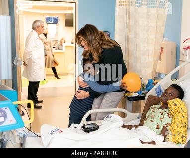 Us-First Lady Melania Trump ist umarmt von einer Jungen, als sie Geschenke an Patienten und Familienmitglieder verteilt während einer Tour von der Kinderklinik in Boston Medical Center November 6, 2019 in Boston, Massachusetts. Stockfoto