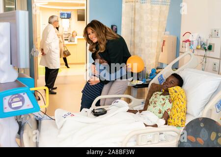 Us-First Lady Melania Trump ist umarmt von einer Jungen, als sie Geschenke an Patienten und Familienmitglieder verteilt während einer Tour von der Kinderklinik in Boston Medical Center November 6, 2019 in Boston, Massachusetts. Stockfoto