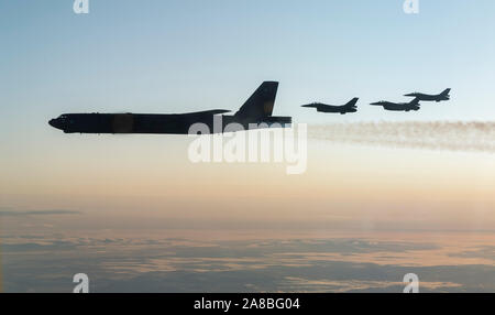 Royal Norwegian Air Force F-16 Fighting Falcon Flugzeuge fliegen neben einem US Air Force B-52 H Stratofortress strategischer Bomber während der gemeinsamen Ausbildung mit der norwegischen Luftwaffe am 6. November 2019 über die Barentssee, Norwegen zugewiesen. Stockfoto