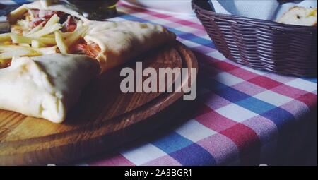 Star Pizza mit Pommes auf runden Holz- essen Vorstand und karierte Tischdecke im italienischen Restaurant. Nahaufnahme Stockfoto