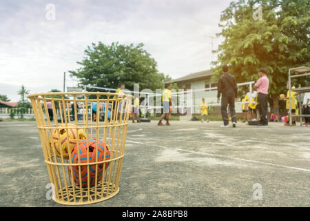 Die takraws im Kunststoff Warenkorb auf dem Zementboden neben dem Feld ist für Schüler verwendet, die in der Physischen Ausbildung Stunden zu üben. Stockfoto