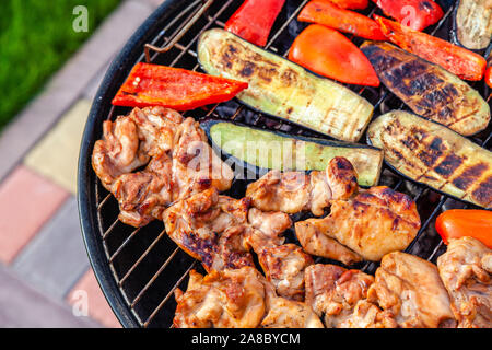 Sortiment von Frische, gesunde farbige Gemüse, Hähnchen Fleisch gegrillt auf BBQ über heißes Feuer Kohlen gegen grüne Gras am Grill. Konzept Sommer Party, Stockfoto