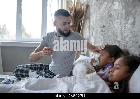 Liebevoller Vater Messung der Körpertemperatur der Töchter Stockfoto