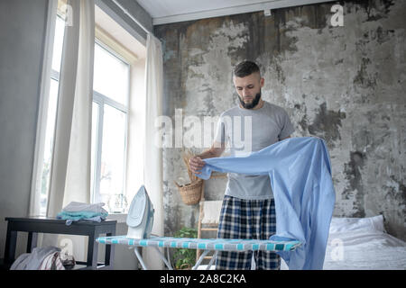 Junge Unternehmer Bügeln sein blaues Hemd Bärtigen Stockfoto