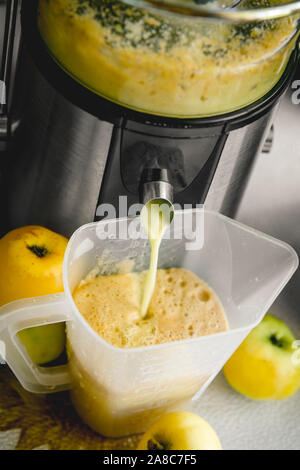 Frischen apfelsaft zu Hause im Herbst zumachen. Frischer Saft fließt durch die Maschinenröhre in eine Kanne. Stockfoto