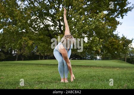 Junge Frau Yoga im Park, Gymnastik, Olympiapark, München, Deutschland Stockfoto