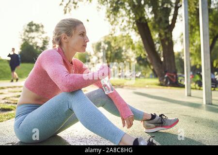 Junge Frau trinkt Wasser, Outdoor Sport, Olympiapark, München, Deutschland Stockfoto