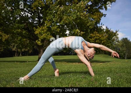 Junge Frau Yoga im Park, Gymnastik, Olympiapark, München, Deutschland Stockfoto