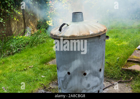 Heimischen garten Verbrennungsanlage verbrennen, produziert eine bescheidene Menge Rauch. Die Verbrennung ist eine Methode für die Entsorgung von nicht kompostierbaren Gartenabfälle. Stockfoto