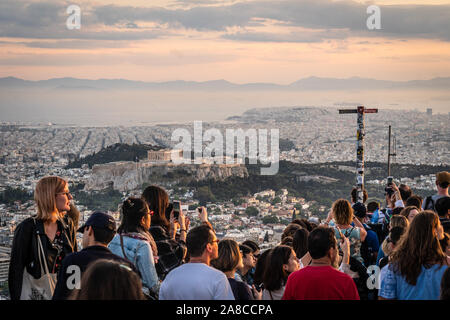 Athen, Griechenland - 16. Mai 2019: Touristen genießen den Sonnenuntergang über der Stadt Athen, die Akropolis und den Parthenon vom Berg Lycabettus. Stockfoto