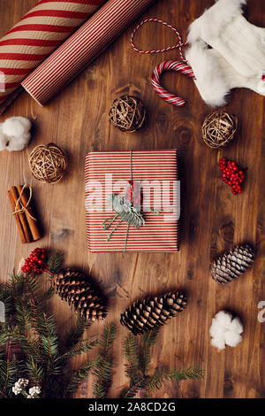 In der Nähe von eingerichteten Weihnachtsgeschenk mit Tannenzapfen und Einwickeln von Dokumenten liegen auf dem hölzernen Tisch Stockfoto