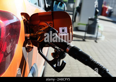 Pumpen Benzin in orange Auto an einer Tankstelle. Zu Auto mit Kraftstoff in Tankstelle füllen. Diesel Inschrift. Close Up. Stockfoto