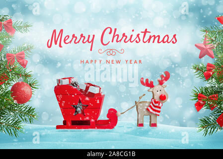 Santa's Reindeer sleigh voller Geschenke im Schnee. Frohe Weihnachten Grußkarte mit niedlichen Spielzeug Komposition. Weihnachtsbaum mit Dekorationen neben. Stockfoto