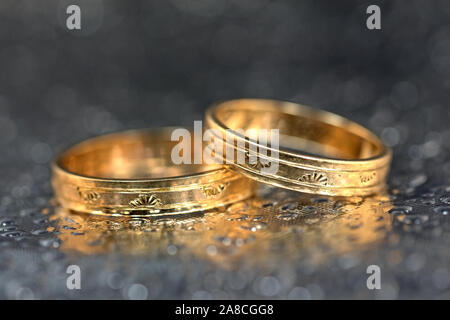 Zwei goldene Hochzeit Ringe vor dunklem Hintergrund Stockfoto