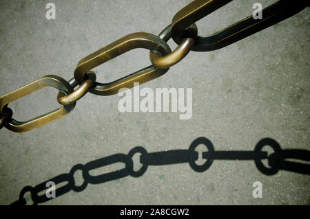 Details Nahaufnahme der dicken schweren Kette aus verwittertem Bronze mit knackigem, sich wellenden Schatten Stockfoto