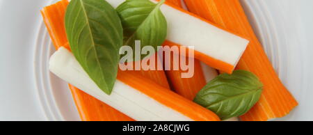 Sechs frische Surimi mit einem Blatt Basilikum auf einer Platte Stockfoto