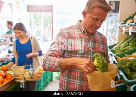 Männliche und weibliche Kunden mit Warenkorb kaufen frische In der organischen Farm Shop erzeugen Stockfoto