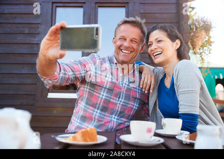 Reifes Paar im Garten Center Cafe unter Selfie auf Handy Stockfoto