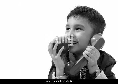 Nachdenklich cute Boy glücklich lächelnd, während sie ein altes Telefon und Essen von Apple Stockfoto