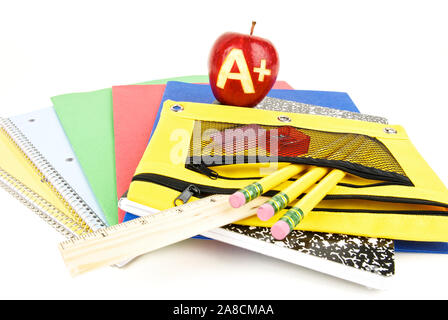 Eine in einen roten apfel gehauene Klasse, die auf Notebooks und Schulartikeln sitzt Stockfoto