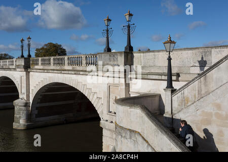 Vom Südufer der Themse ist die Architektur der Kingston Bridge, wo ein Fußgänger seine Schritte klettert gesehen, am 7. November 2019 in Kingston, London, England. Eine Kreuzung hat am Kingston existiert seit der Antike und dieser Version von Kingston Bridge von Herbert für £ 26.800 konstruiert wurde und durch die Herzogin von Clarence (die zukünftige Königin Adelaide) am 17. Juli 1828 eröffnet. Von Portland aus Stein gebaut, es besteht aus fünf elliptische Bögen. Stockfoto