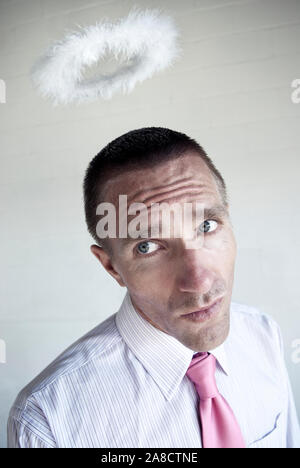 Angel Investor Geschäftsmann vor einem grungy Wand mit einem Heiligenschein schwebt über dem Kopf stehend Stockfoto