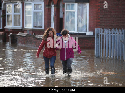 Zwei Menschen laufen durch Hochwasser auf Yarborough Terrasse in Doncaster, Yorkshire, als Teile von England von einem Monat im Wert von Regen in 24 Stunden ausgehalten, mit Kerben von Menschen gerettet oder gezwungen, ihre Häuser zu verlassen, andere über Nacht in einem Einkaufszentrum gestrandet, und Reiseplanung ins Chaos gestürzt. Stockfoto