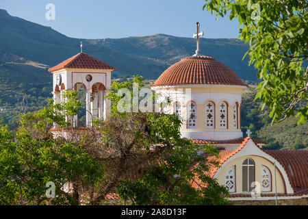 Elos, Chania, Kreta, Griechenland. Glockenturm und Kuppel der griechisch-orthodoxen Kirche, eingerahmt von Bäumen. Stockfoto