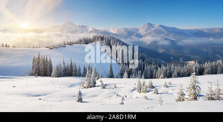 Winterlandschaft an einem sonnigen Morgen in den Bergen. Die Hütten der Hirten auf dem Hügel. Karpaten, Ukraine, Europa. Blick auf den Kamm des moun Stockfoto