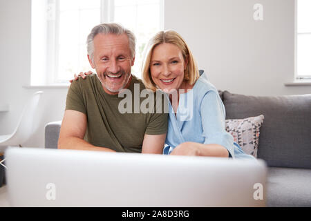 Senior Paar sitzt auf einem Sofa zu Hause Video mit Laptop zusammen Stockfoto